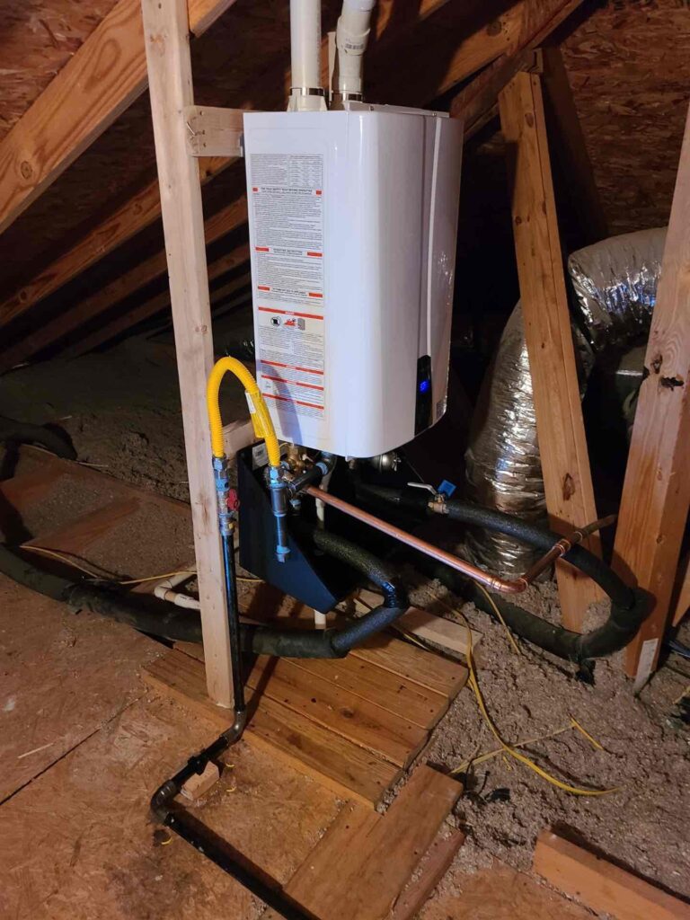 Tankless water heater installation in an attic setting, featuring pipes and connections for efficient hot water service in Greater Austin.