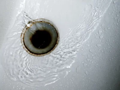 Bathtub drain with water swirling around, highlighting potential plumbing issues related to sewer odors and clogs.