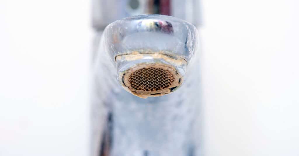 Dirty faucet with limescale buildup, illustrating potential causes of discolored water in plumbing systems.