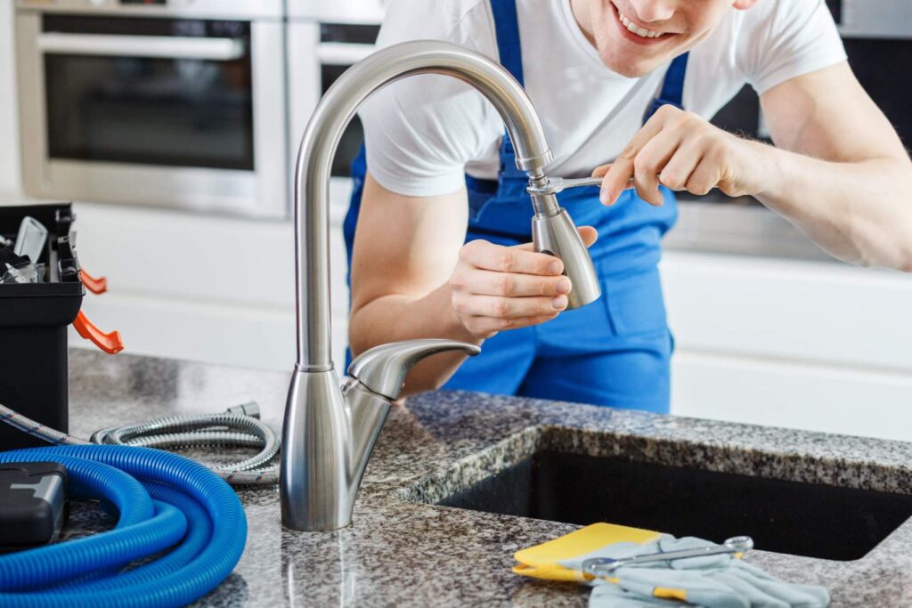Plumber installing modern kitchen faucet with tools and hoses on granite countertop, showcasing expert plumbing service and precision workmanship in North Austin.