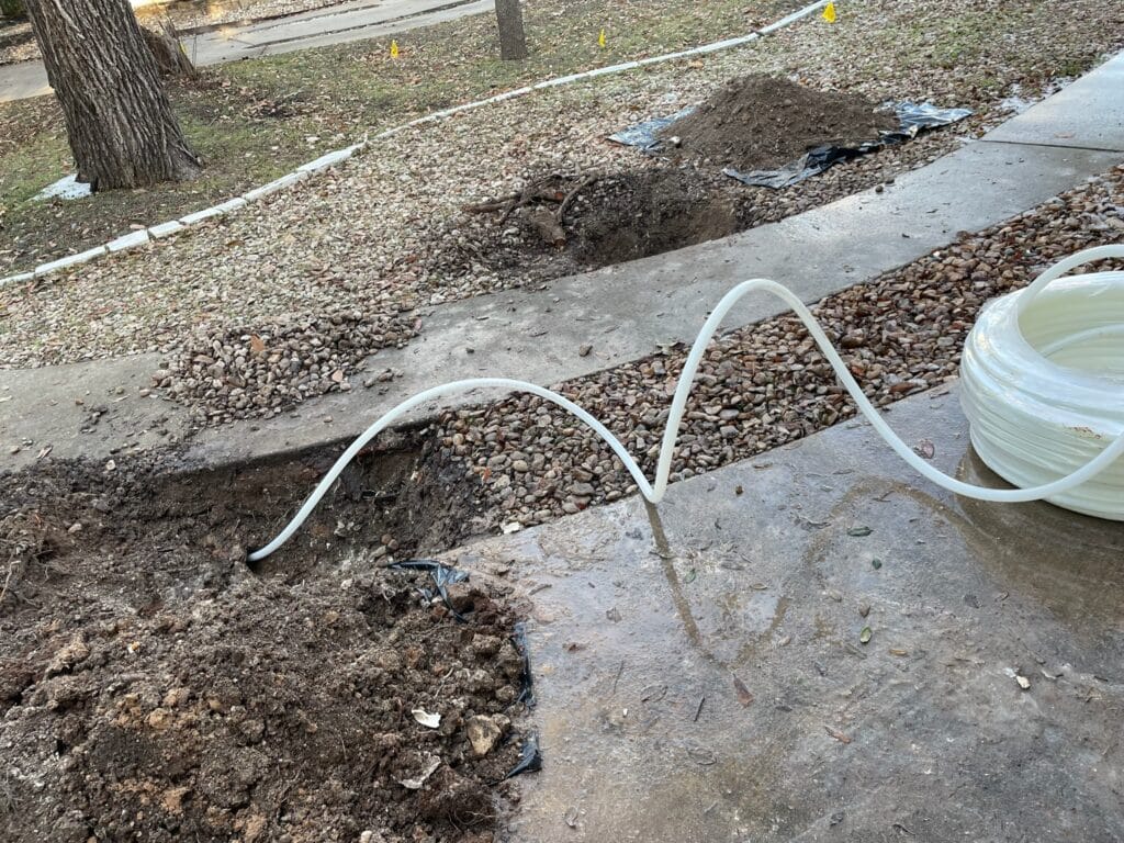 Trenchless water line replacement process showing excavated area, flexible piping, and minimal disruption to landscaping.