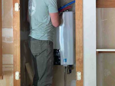 Plumber repairing a water heater in a residential setting, highlighting the importance of professional service for no hot water issues in West Lake Hills, TX.