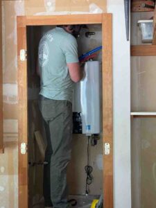 tankless water heater mounted on wall with hot water flowing from faucet