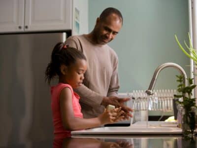 family filling glasses with filtered tap water at home kitchen sink